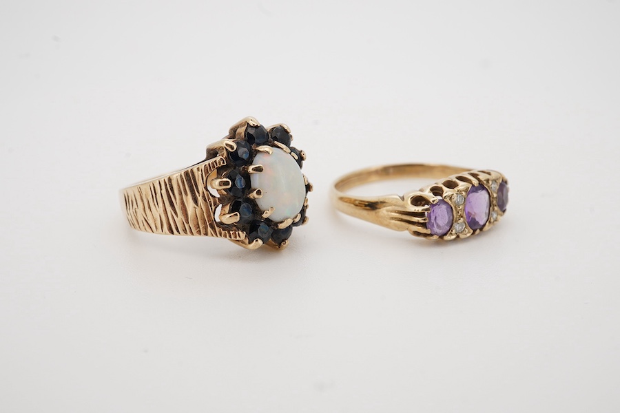 A 1970's textured 9ct gold, white opal and sapphire set oval cluster ring, size L, together with a modern 9ct gold and three stone amethyst set ring, with diamond chip spacers, size M/N, gross weight 7 grams. Condition -